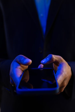 Vertical image of hands of biracial businessman with smartphone with copy space on black background. Technology, digital networks, global connections and communication metaverse.の写真素材