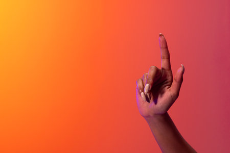 Hand of biracial woman pointing with finger with copy space on neon red to orange background. Technology, digital networks, global connections and communication metaverse.の写真素材