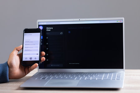 Biracial businessman using smartphone and data processing on laptop screen. Technology, digital networks, global connections and communication metaverse.の写真素材