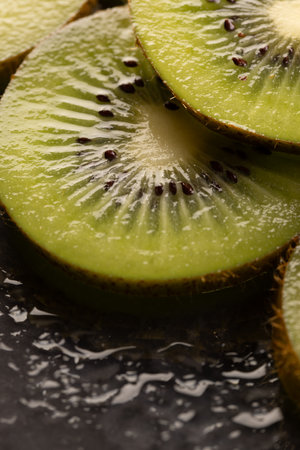Micro close up of sliced kiwi fruits with water drops and copy space on black background. Micro photography, food, texture and colour concept.の写真素材