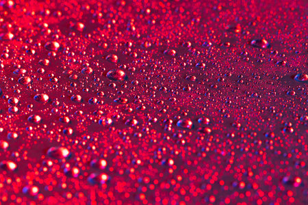 Micro close up of water drops with copy space on red background. Micro photography, liquid, texture and colour concept.の写真素材