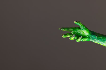 Green monster hand with black nails reaching on grey background. Halloween, tradition and celebration concept.の写真素材
