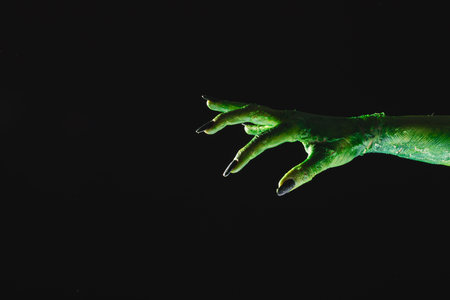 Green monster hand with black nails reaching on grey background. Halloween, tradition and celebration concept.の写真素材