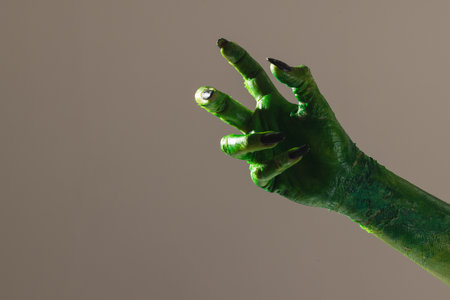 Green monster hand with black nails making gesture on grey background. Halloween, tradition and celebration concept.の写真素材