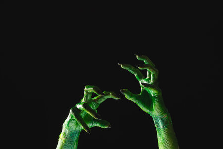 Green monster hands with black nails reaching on black background. Halloween, tradition and celebration concept.の写真素材