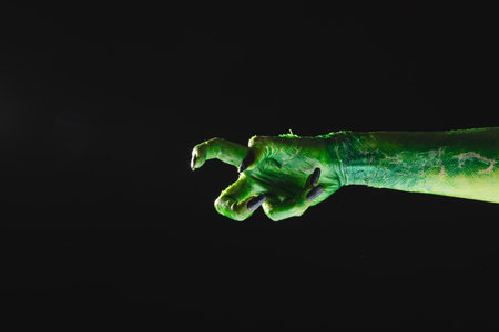 Green monster hand with black nails reaching on black background. Halloween, tradition and celebration concept.の写真素材