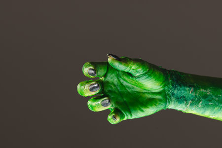 Green monster hand with black nails reaching on grey background. Halloween, tradition and celebration concept.の写真素材