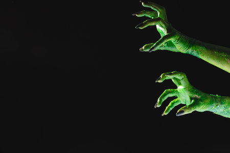 Green monster hands with black nails reaching on black background. Halloween, tradition and celebration concept.の写真素材