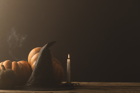 Pumpkins and witch hat and burning candle with copy space on grey background. Fall, autumn, halloween, tradition and celebration concept.の写真素材