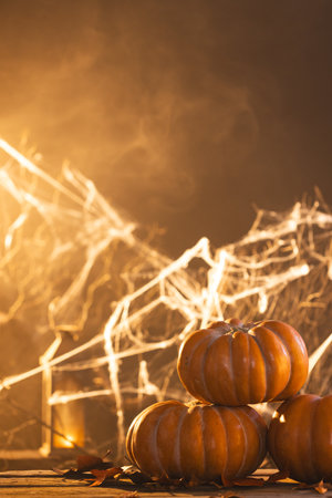 Vertical image of pumpkins and spiderweb decorations with copy space on orange background. Fall, autumn, halloween, tradition and celebration concept.の写真素材