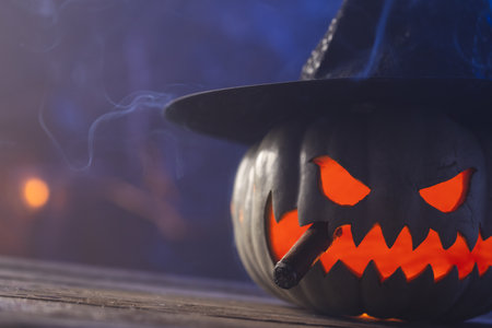 Carved pumpkin wearing witch hat with copy space on blue background. Fall, autumn, halloween, tradition and celebration concept.の写真素材