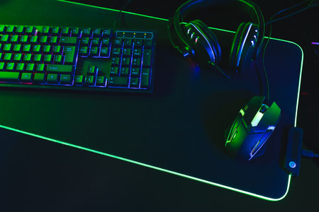 Composite of computer, keyboard with video game accessories with copy space on neon background....