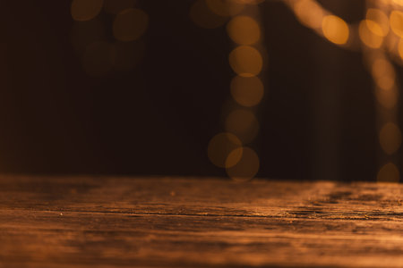 Yellow bokeh blurred lights with copy space and wooden surface on dark background. Light, colour and shape concept digitally generated image.の写真素材