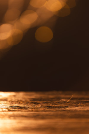 Vertical image of yellow bokeh blurred lights with copy space and wooden surface on dark background. Light, colour and shape concept digitally generated image.の写真素材