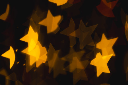 Yellow star bokeh lights with copy space on dark background. Light, colour and shape concept digitally generated image.の写真素材