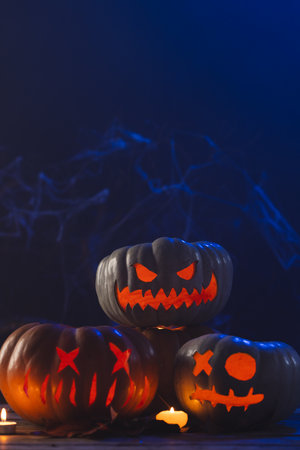 Vertical image of three carved pumpkins and candles with copy space on blue background. Fall, autumn, halloween, tradition and celebration concept.の写真素材
