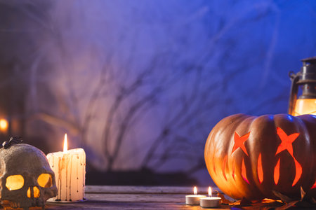 Carved pumpkin, skull and candle with copy space on blue background. Fall, autumn, halloween, tradition and celebration concept.の写真素材
