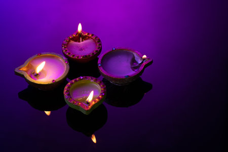 Close up of four diwali candles with copy space on purple background. Diwali, festival of lights, religion, hindu tradition and celebration.の写真素材