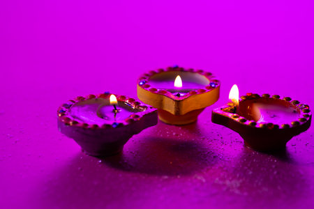Close up of three diwali candles with copy space on purple background. Diwali, festival of lights, religion, hindu tradition and celebration.の写真素材