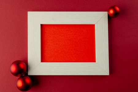 Red baubles christmas decorations and wooden frame with copy space on red background. Christmas,...