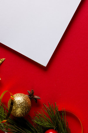 Vertical image of christmas decorations with wthie card and copy space on red background. Christmas, decorations, tradition and celebration concept.の写真素材