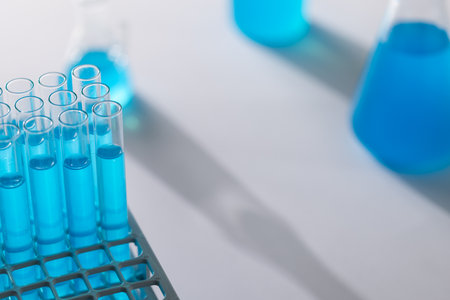 Close up of laboratory test tubes with blue liquid and copy space on white background. Laboratory, science, research and chemistry concept.の写真素材