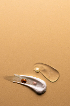 Vertical image of beauty product white cream clear serum smudge with copy space on brown background....