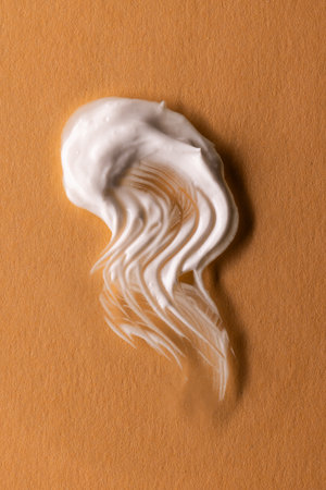 Vertical image of beauty product white cream smudge with copy space on brown background. Health and beauty, beauty product, make up and colour concept.の写真素材