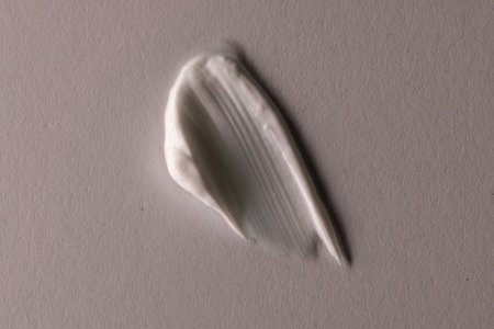 Close up of beauty product white cream smudge with copy space on brown background. Health and...