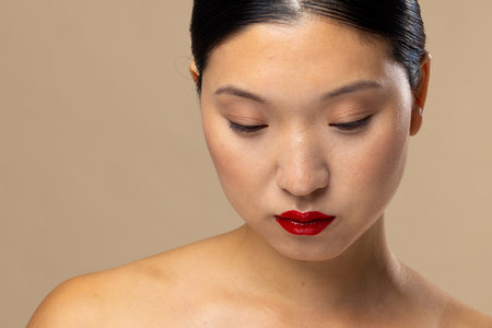 Asian woman wearing red lipstick and nail polish on beige background. Cosmetics, makeup, female fashion and beauty, unaltered.の写真素材