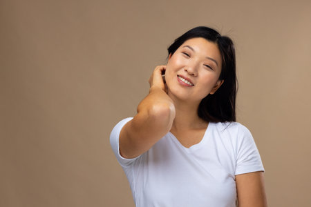 Portrait of asian woman wearing natural makeup and white t-shirt on beige background, copy space. Cosmetics, makeup, female fashion and beauty, unaltered.の写真素材