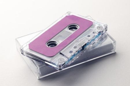 Close up of purple cassette tape and white box on white background. Music, sound, listening,...