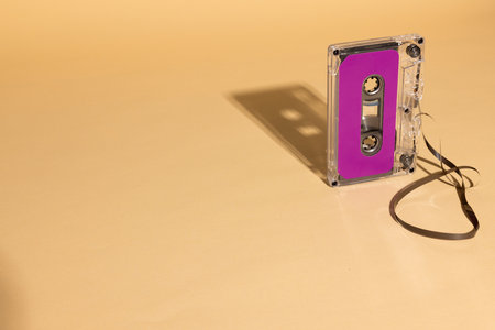 Close up of purple cassette tape with copy space on beige background. Music, sound, listening,...
