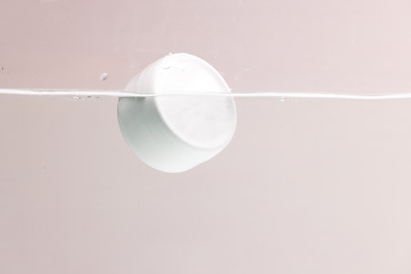 Beauty product tub floating in water with copy space background on pink background. Health and beauty, make up and beauty concept.の写真素材