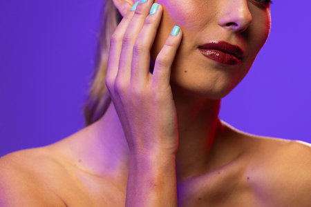 Caucasian woman wearing red lipstick and blue nail polish on blue background. Cosmetics, makeup, female fashion and beauty, unaltered.の写真素材