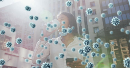 Covid-19 cells floating against african american woman with lowered face mask drinking coffee. coronavirus covid 19 pandemic conceptの写真素材