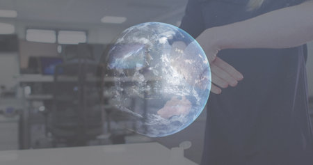 Image of globe spinning with woman disinfecting hands in office. Healthcare and protection during...