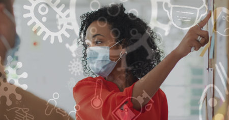 Image of floating covid-19 icons with colleagues in office wearing face masks. Healthcare and protection during coronavirus covid 19 pandemic, digitally generated imageの写真素材