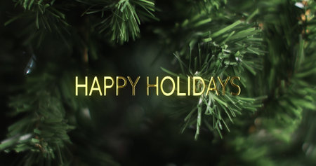 Happy holidays text in gold over close up christmas tree background. Christmas, tradition, greetings and celebration digitally generated image.の写真素材