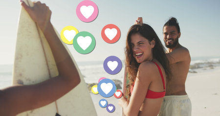 Image of heart digital icons over friends with surfboards on beach. digital interface, social media...