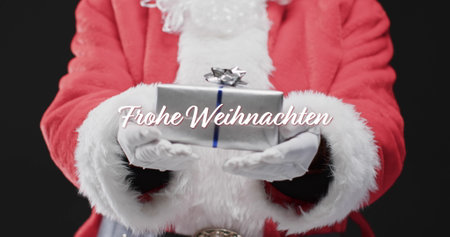 Frohe weihnachten text in white over midsection of father christmas holding present. Christmas, tradition, german, greetings and celebration digitally generated image.の写真素材