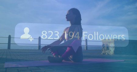 Image of rising number of followers over woman meditating on promenade by the sea. Digital interface...