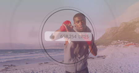 Speech bubble with increasing likes against african american male boxer practicing boxing at beach....