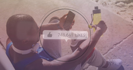 Image of media icons over african american man using smartphone at beach. health and fitness concept...