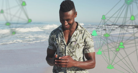 Image of spinning networks with social media digital icons over man using smartphone on beach. digital interface, social media and global networking concept digitally generated image.の写真素材