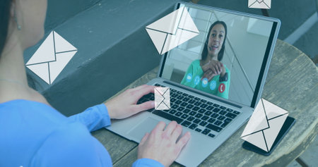 Image of digital envelope mail icons over woman using laptop on image call. Digital interface global connection and communication concept digitally generated image.の写真素材