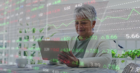 Image of financial data processing over senior woman using tablet at home. global finance, business...