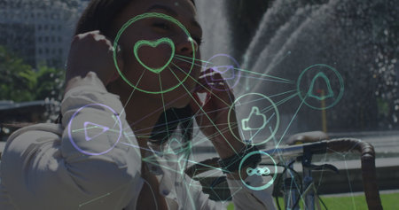 Image of network of connections with icons over woman putting earphones on in city. global...