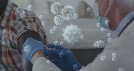 Image of covid 19 cells over man receiving vaccination wearing face mask. global covid 19 pandemic, health and medicine concept digitally generated image.の写真素材