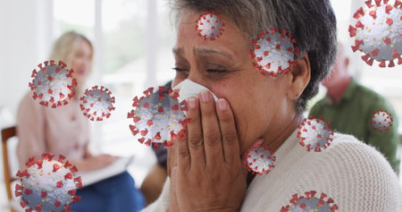 Multiple covid-19 cells floating against african american woman crying and blowing her nose. medical consultation during covid 19 pandemic conceptの写真素材